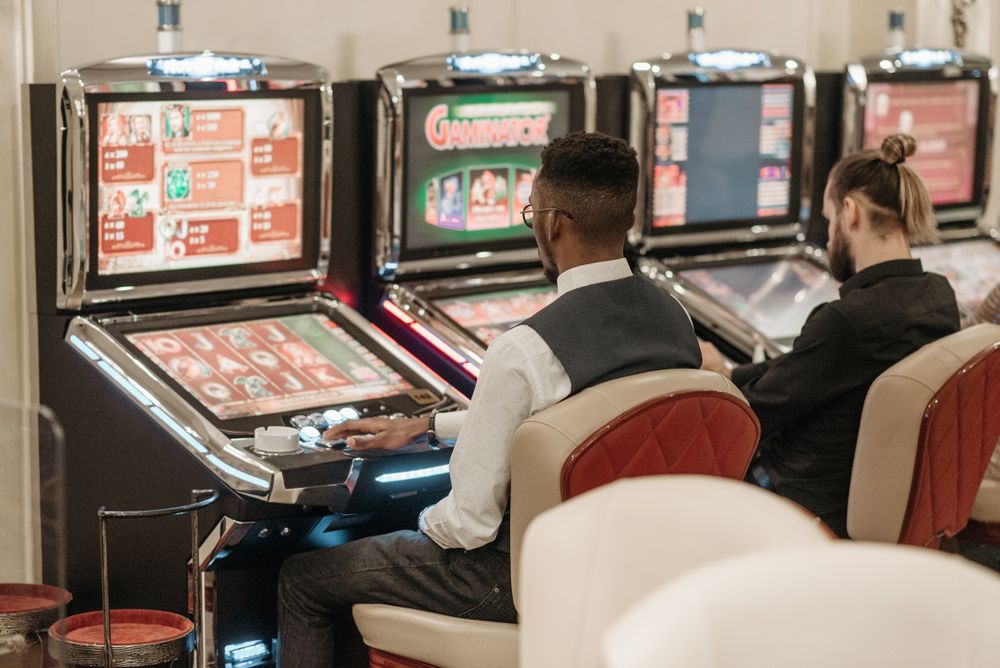 Dua pemain duduk bermain mesin slot di kasino