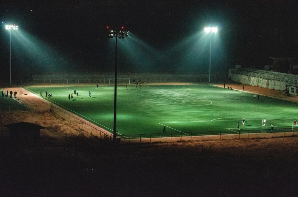 Lapangan sepak bola malam hari dengan lampu sorot menyala